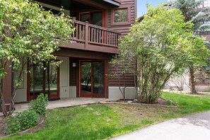 A two-story building with a balcony, large sliding glass doors, and a small garden area. - Creekside Condo at the Base of Beaver Creek (Avon)