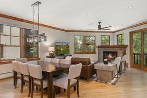 Une salle à manger spacieuse avec une table et des chaises en bois, une cheminée et de grandes fenêtres.