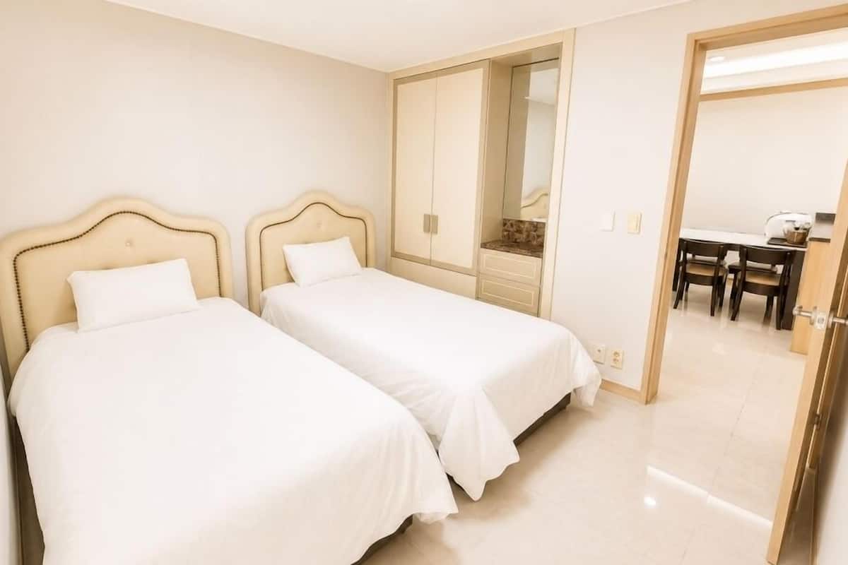 Hotellihuone, jossa on kaksi sänkyä, ruokailutila ja peili.