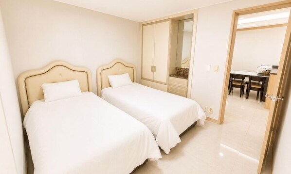 Una habitación de hotel con dos camas, un área de comedor y un espejo.