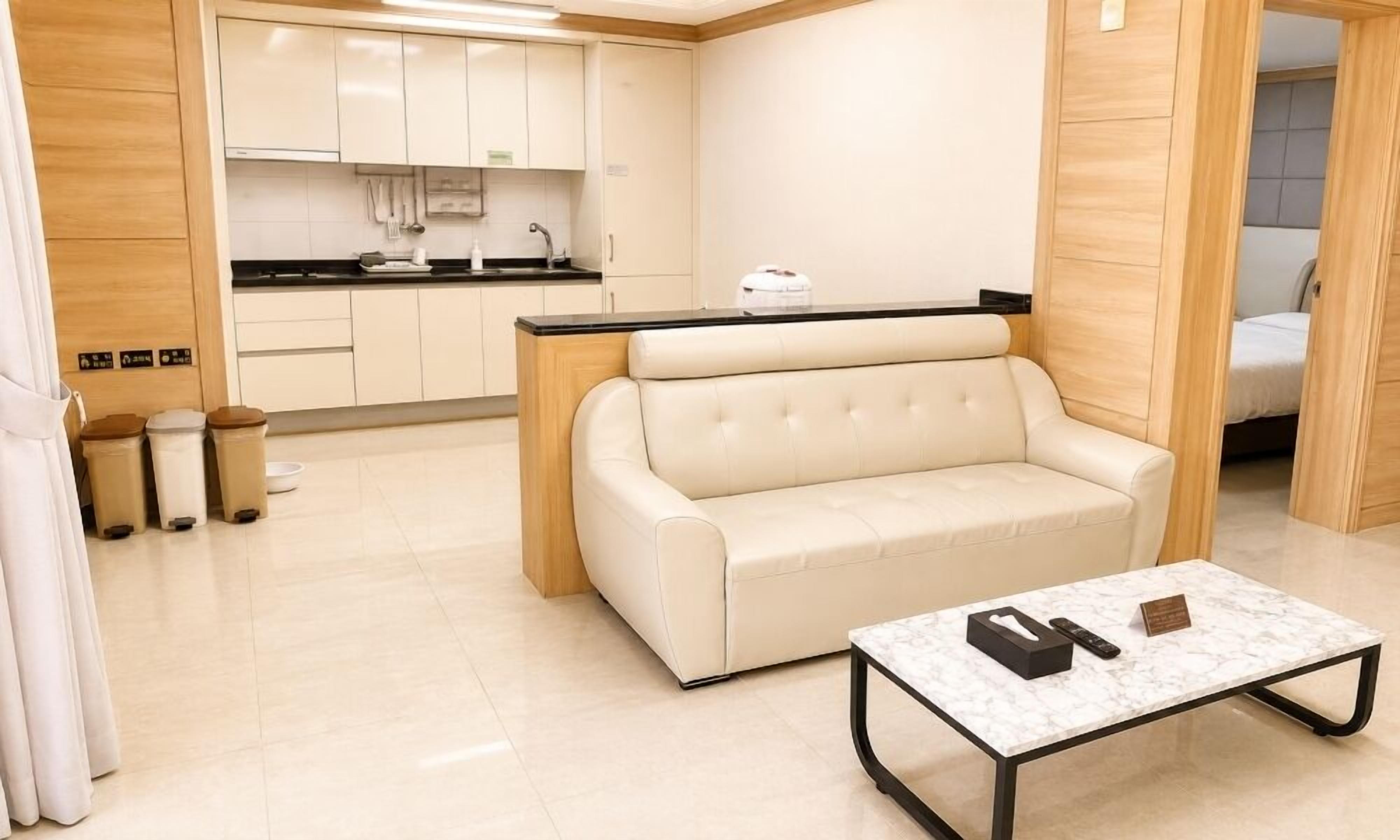 Un espacio habitable compacto con kitchenette, un sofá, una mesa de centro y una cama en la habitación contigua.