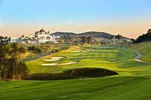 Un campo de golf con búnkeres, un camino serpenteante y un edificio de arquitectura abovedada al fondo.