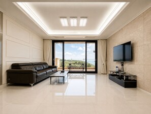 A modern living room with a sofa, a flat-screen TV, and a balcony with a table and chairs. - Seosansoo Golf & Resort (Seosan)