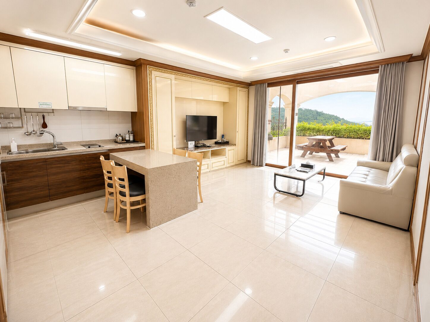 A modern kitchen with a central island, a dining area with a table and chairs, a sofa, and a large sliding glass door leading to an outdoor patio.