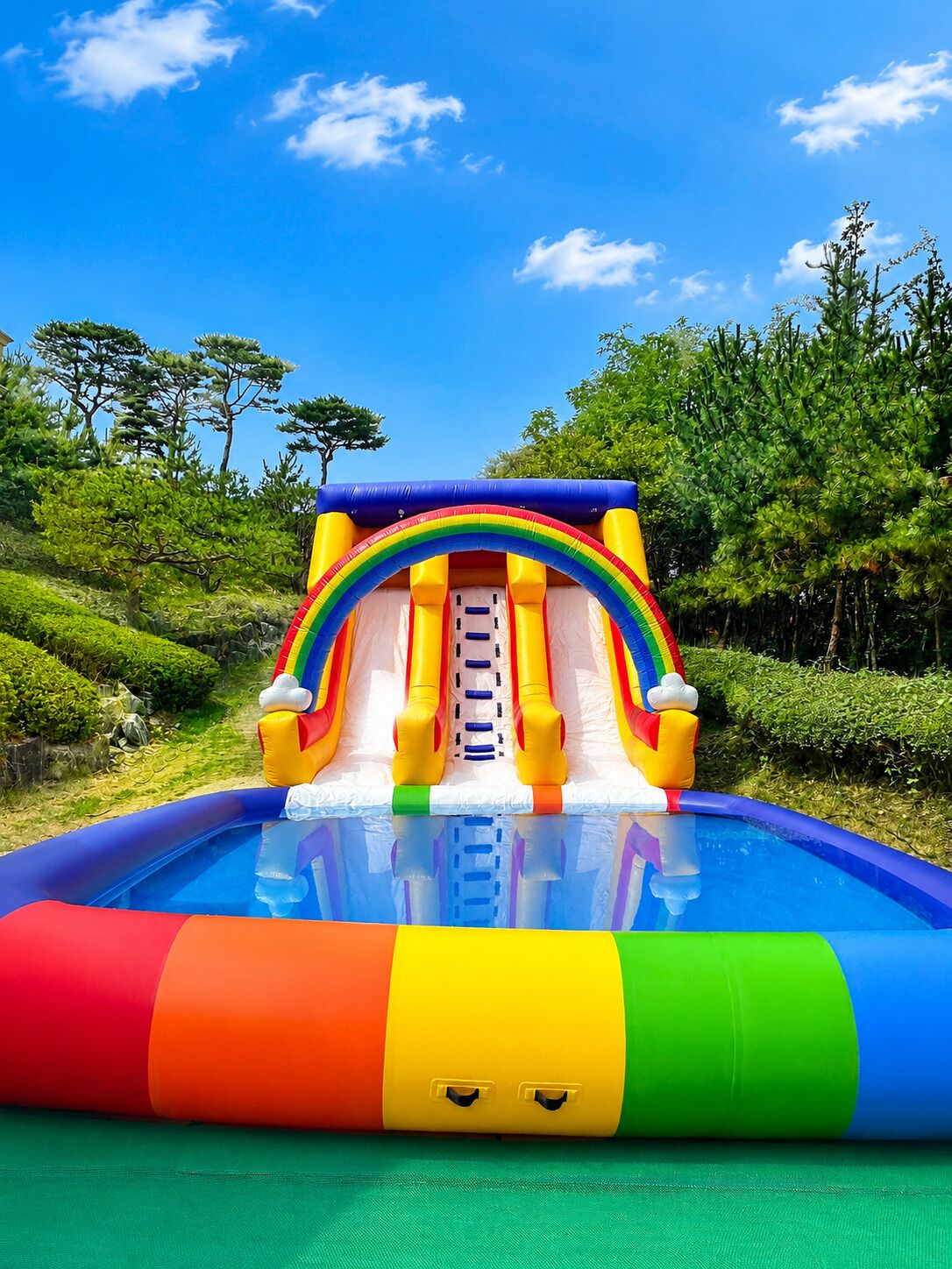 An inflatable slide with a rainbow arch and a pool at the bottom.