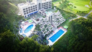 A large resort with multiple buildings, a central pool, and a golf course in the background. - Seosansoo Golf & Resort (Seosan)