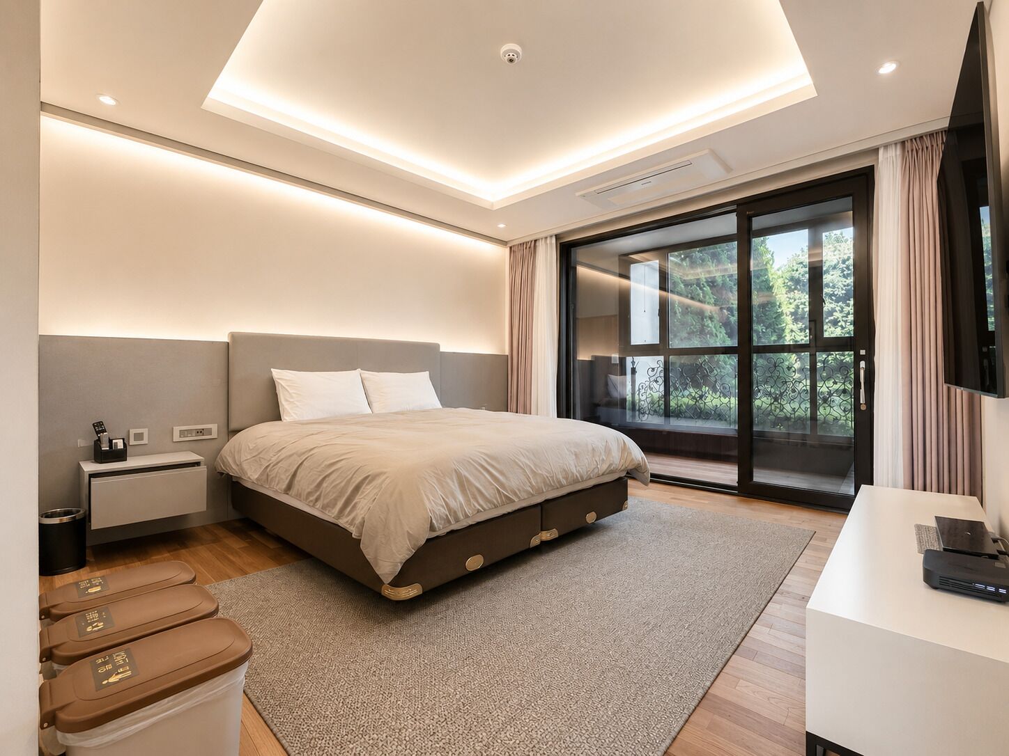 Un dormitorio moderno con una cama grande, una mesita de noche, un escritorio y una puerta corrediza al balcón.