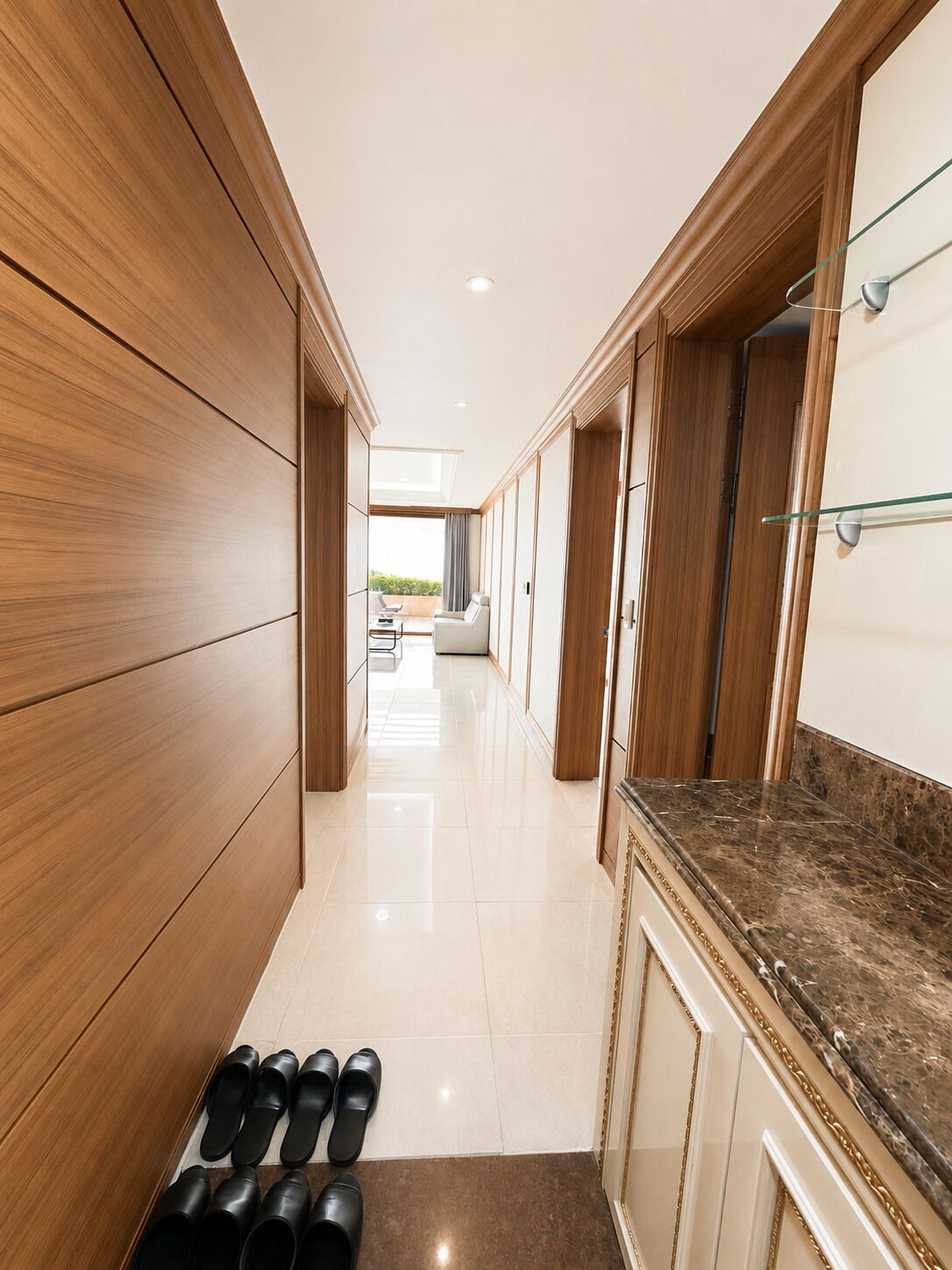 A hallway with wooden paneling, a marble countertop, and a row of black shoes.