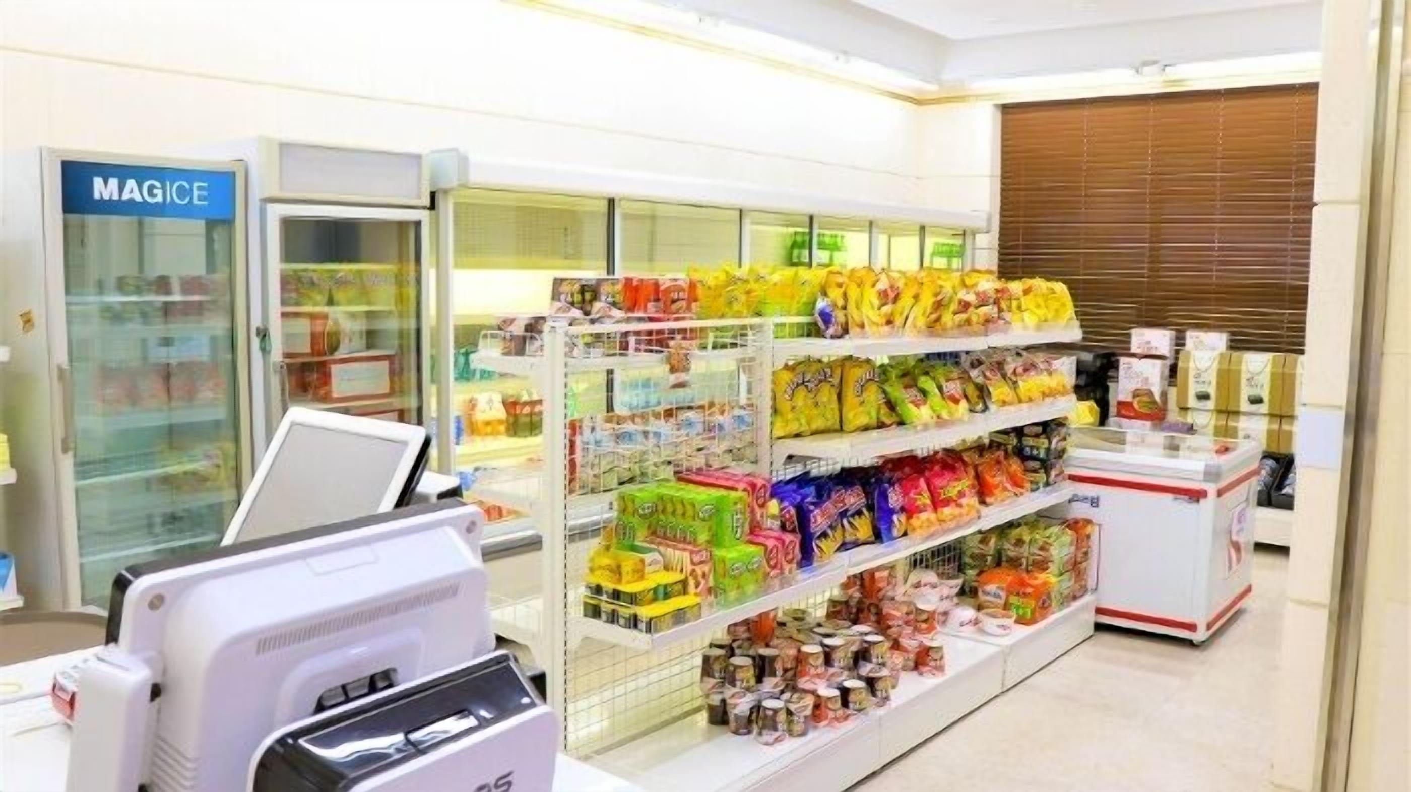 Un supermercado con estantes llenos de productos para el aperitivo y una sección refrigerada.