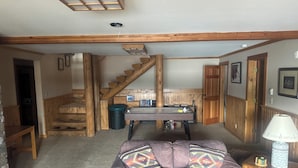 Una sala acogedora con una escalera de madera, un sofá con cojines estampados y una lámpara sobre una mesita.
