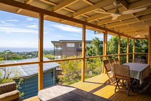A covered outdoor area with a table and chairs, a view of a house, and a balcony railing. - Fourlees Breeze - Ocean Views - Sleeps 11 (Point Lookout)