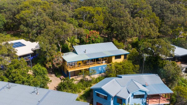 A house with a large balcony, surrounded by dense trees. - Fourlees Breeze - Ocean Views - Sleeps 11 (Point Lookout)