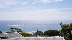 A coastal view with a clear sky, ocean, and a building with a sloped roof. - Fourlees Breeze - Ocean Views - Sleeps 11 (Point Lookout)