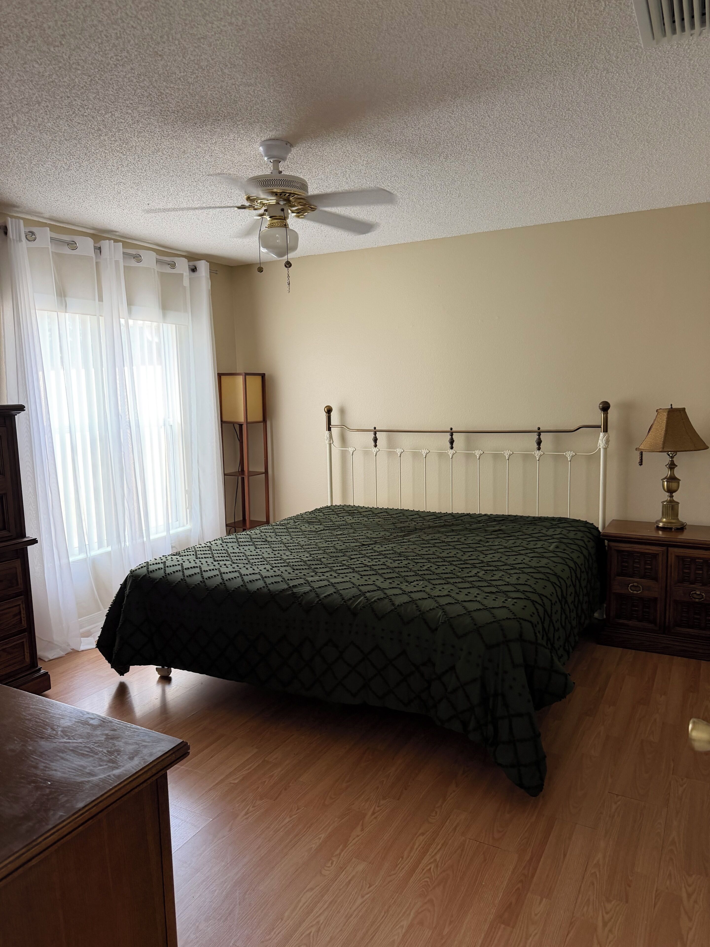 Ein Schlafzimmer mit Bett, Deckenventilator, Nachttisch und Lampe.