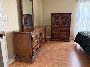 A bedroom with a wooden dresser, a mirror, and a bed. - Berea Villa's, Polo Ridge, Stunning Courtyard Villa, Golf Cart included! (The Villages)