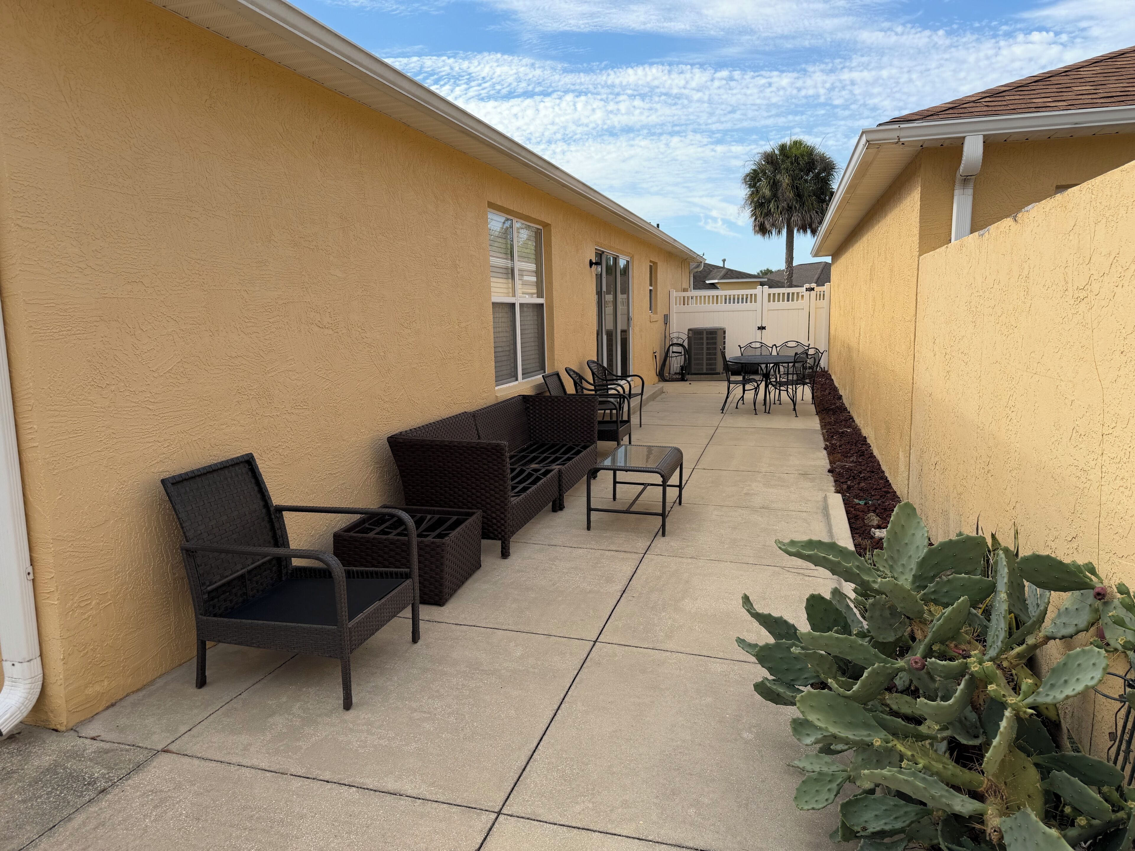 A patio area with outdoor furniture, a cactus plant, and a white fence.