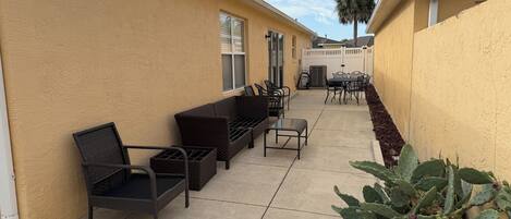 A patio area with outdoor furniture, a cactus plant, and a white fence.