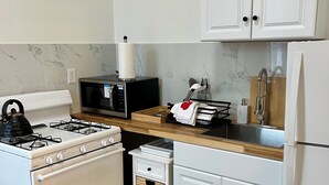 Keittiössä on liesi, mikroaaltouuni, jääkaappi ja valkoiset kaapit.