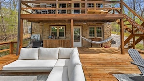 Eine Holzterrasse mit einer weißen Couch, einer Hängematte und einem Sessel.
