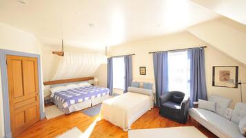 A bedroom with a bed, a chair, a sofa, and a window with curtains.