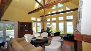 A spacious living room with a high ceiling, large windows, and a fireplace. - Little Shemouge Country Inn (Little Shemogue)