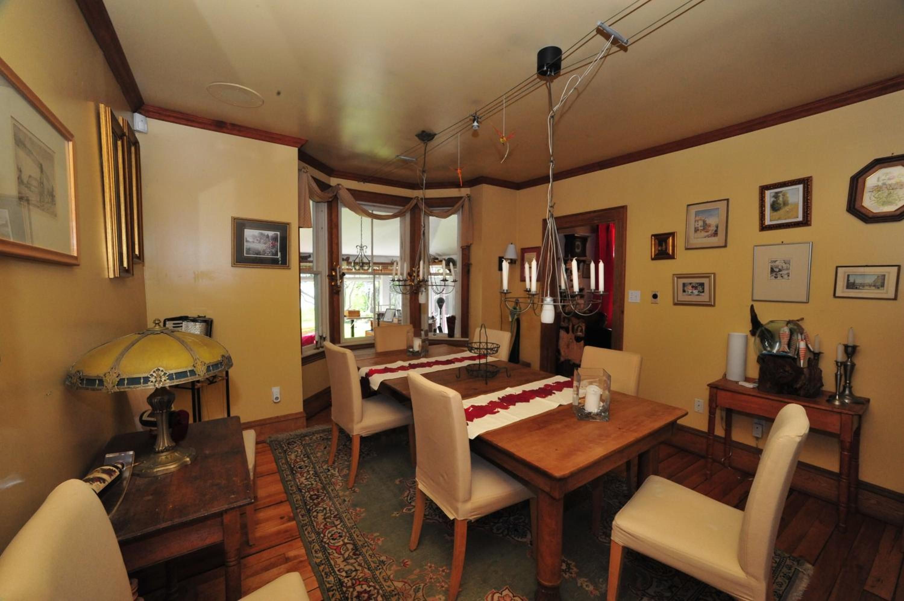A dining room with a wooden table, chairs, a chandelier, and a rug.
