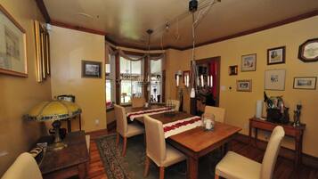 A dining room with a wooden table, chairs, a chandelier, and a rug.