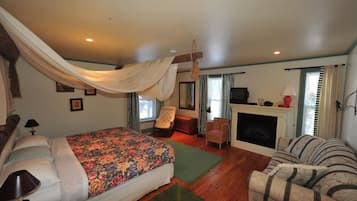 A bedroom with a bed, a chair, a sofa, a fireplace, and a television.
