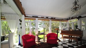 A room with a checkered floor, two red chairs, a wooden bench, a sewing machine, and a piano. - Little Shemouge Country Inn (Little Shemogue)