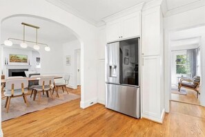 Eine moderne Küche mit weißen Schränken, einem Edelstahlkühlschrank und einem Essbereich mit Holzkohle und Teppich.