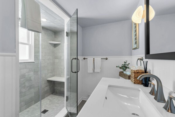 A modern bathroom with a glass shower enclosure, a white sink, and a towel rack. - Prof Managed with Backyard + 5 Blocks to Beach (Bradley Beach)