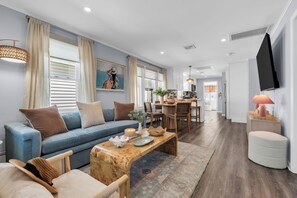 A modern living room with a sofa, coffee table, and dining area. - Prof Managed with Backyard + 5 Blocks to Beach (Bradley Beach)