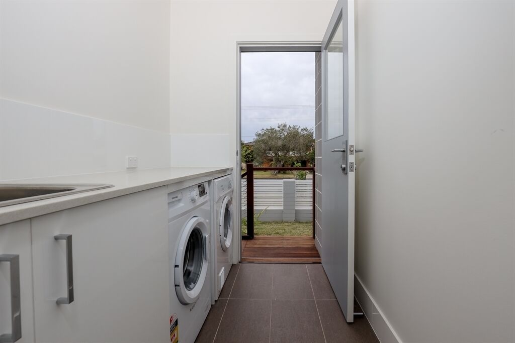 A laundry area with a washing machine, a drying rack, and a door leading to a backyard.