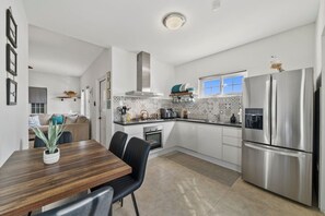 Eine moderne Küche mit Essbereich, Edelstahlgeräten und einer gefliesten Spritzschutzwand.
