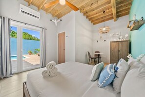 Ein Schlafzimmer mit Bett, Schreibtisch, Stuhl, Kleiderschrank und Blick ins Freie.