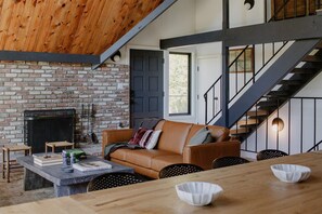 Una sala acogedora con chimenea de ladrillo, un sofá de cuero y una mesa de comedor con sillas.