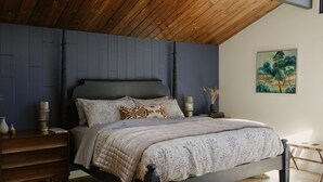 Ein Schlafzimmer mit einem Bett, einem Holzkopfende, Nachttischen und einem Bild an der Wand.