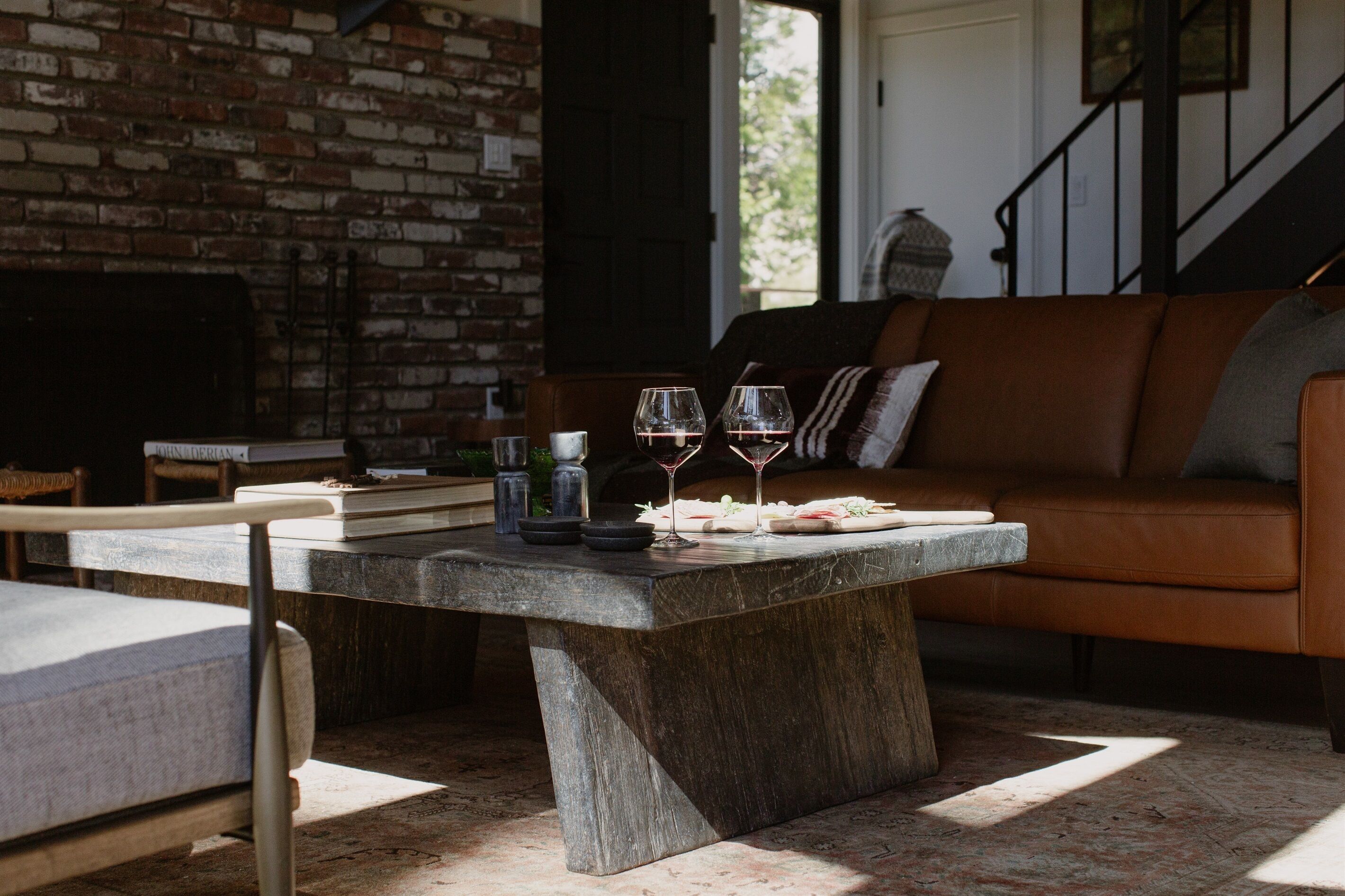 A stone table with glasses and food, a brick wall, and a leather sofa.