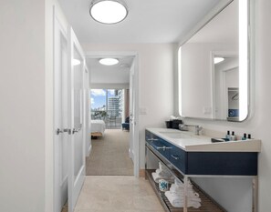 Une salle de bain d’hôtel avec un grand miroir, un lavabo et un porte-serviettes.