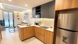 Eine moderne Küche mit Holzschränken, einem Edelstahlkühlschrank, einer eingebauten Mikrowelle und einem Spülbecken.