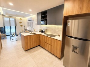 A modern kitchen with wooden cabinets, a stainless steel refrigerator, a built-in microwave, and a sink. - Mr. W | Cozy and Modern Loft at Torre Scala (Guadalajara)
