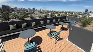 Eine Dachterrasse mit Sitzgelegenheiten und Tischen mit Blick auf die Stadt.