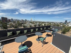 A rooftop terrace with seating and tables, overlooking a cityscape. - Mr. W | Cozy and Modern Loft at Torre Scala (Guadalajara)
