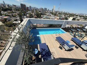 A rooftop pool with lounge chairs, surrounded by a cityscape view. - Mr. W | Cozy and Modern Loft at Torre Scala (Guadalajara)