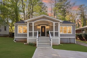 Ein zweistöckiges Haus mit Veranda, mittlerem Eingang und kleinem Vorgarten.