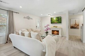 Una sala moderna con chimenea, un sofá y un televisor montado en la pared.