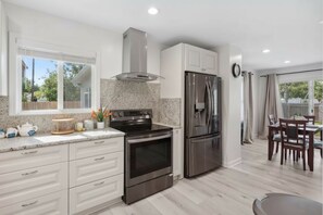 Eine moderne Küche mit Edelstahl-Kühlschrank, Dopplofen und Granit Arbeitsplatte.
