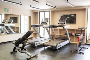 Une salle de sport équipée de tapis de course, d’un vélo d’appartement et d’autres appareils d’exercice.
