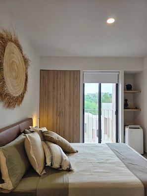 Une chambre avec un lit, une armoire, une petite étagère et une vue sur l’extérieur.