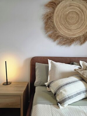 Ein Schlafzimmer mit einem Bett, Kissen, einem Nachttisch und einem wandmontierten, runden Gewebestück.